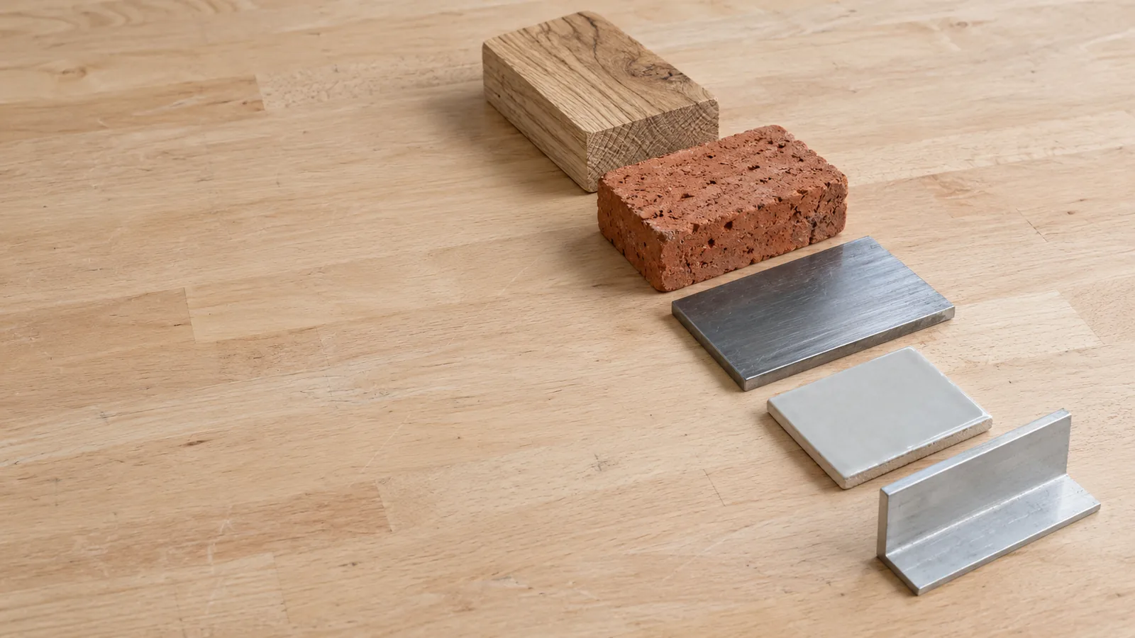 Werkstoffproben aus Holz, Ziegel, Stahl, Fliese und Aluminium auf einer Werkbank